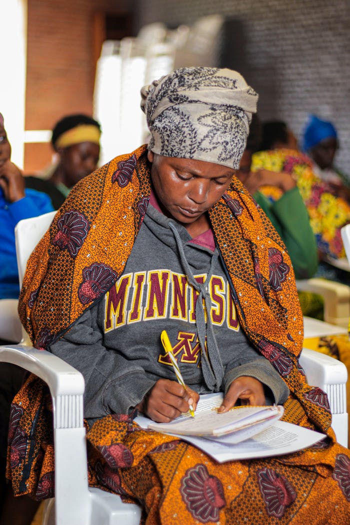Woman in colorful African attire taking notes during a session in Gitega, Burundi.