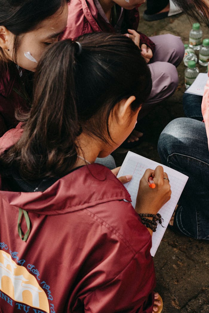 Young woman writing notes in a group setting, interactive study or gathering atmosphere.