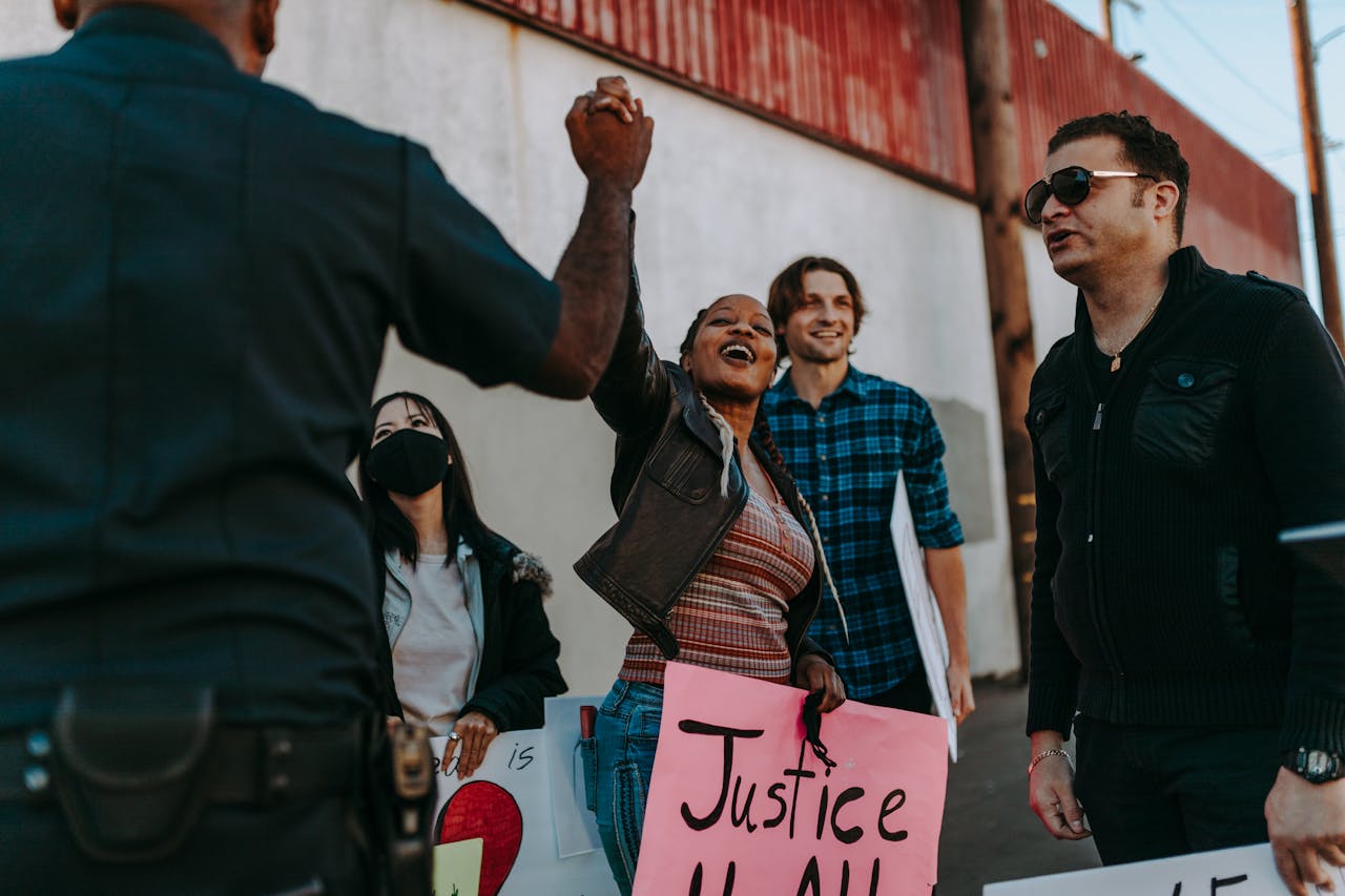 A diverse group rallies with signs at a peaceful protest outdoors. Positive interaction with police enhances community spirit.